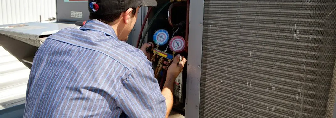 HVAC technician servicing a condenser unit in Berkley