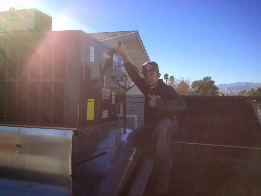 HVAC technician performing Air Duct Cleaning on a rooftop unit in Berkley